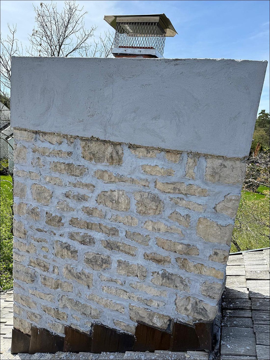 Stone chimney with new crown and flashing at the roofline